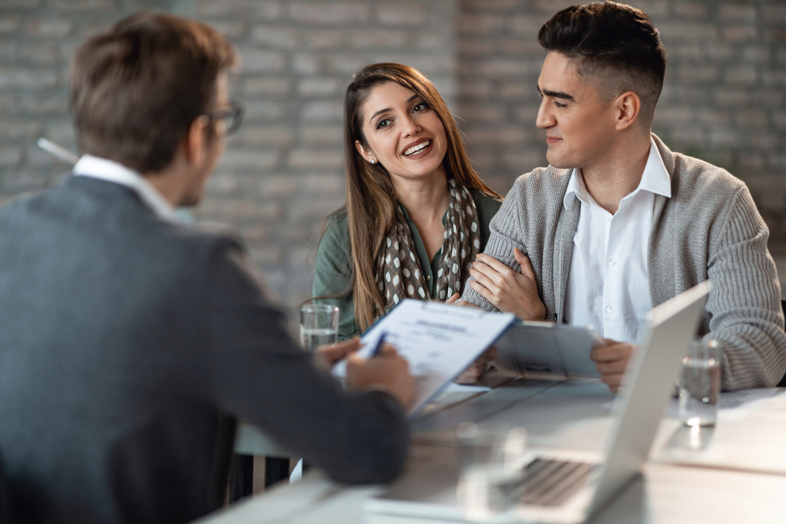 Young happy couple having a meeting with real estate agent in the office. Focus is on woman.